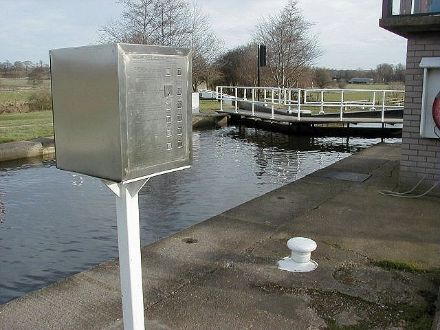 Lock gate on the Aire & Calder Navigation Canal network. The gate is closed and water rests up to the top of its full height. In the foreground we can see a silver-coloured metal control box on a white metal post.