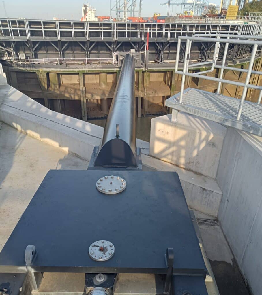Closed flood gates at the Port of Tilbury. A black hydraulic arm projects from the quayside to operate the gate mechanism.